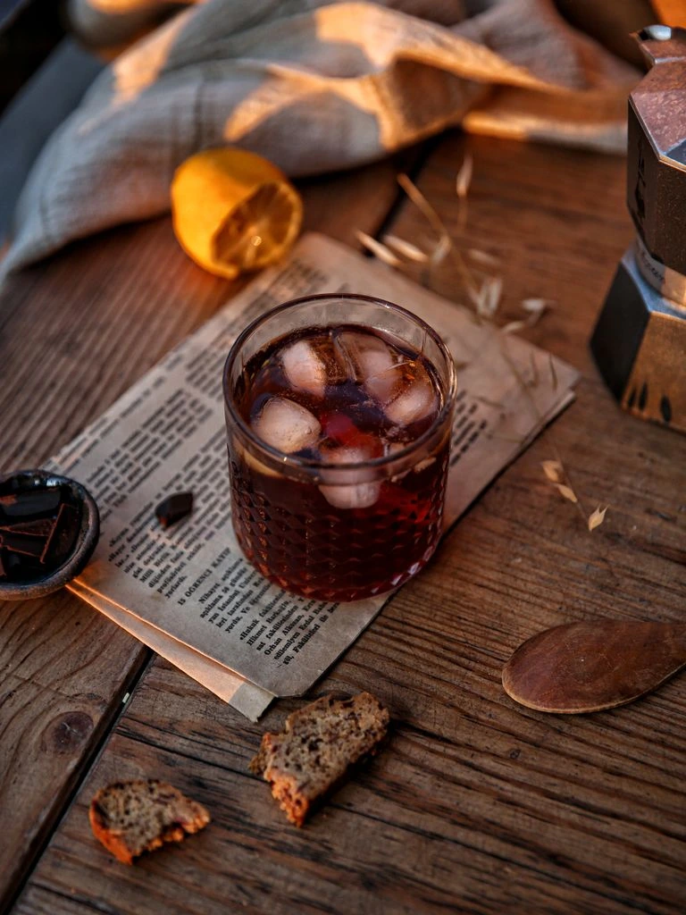 A tulip glass of Irish whiskey on an oak bar top with a tasting notebook and brass jigger