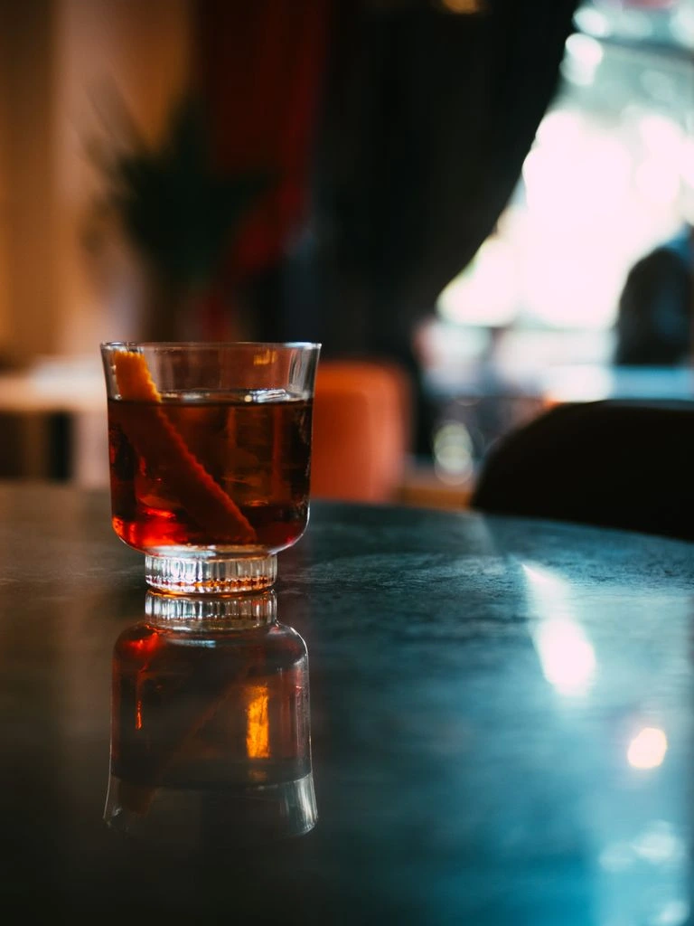 A stirred Negroni in a coupe glass with an orange peel twist, photographed at the Boobar test bar.